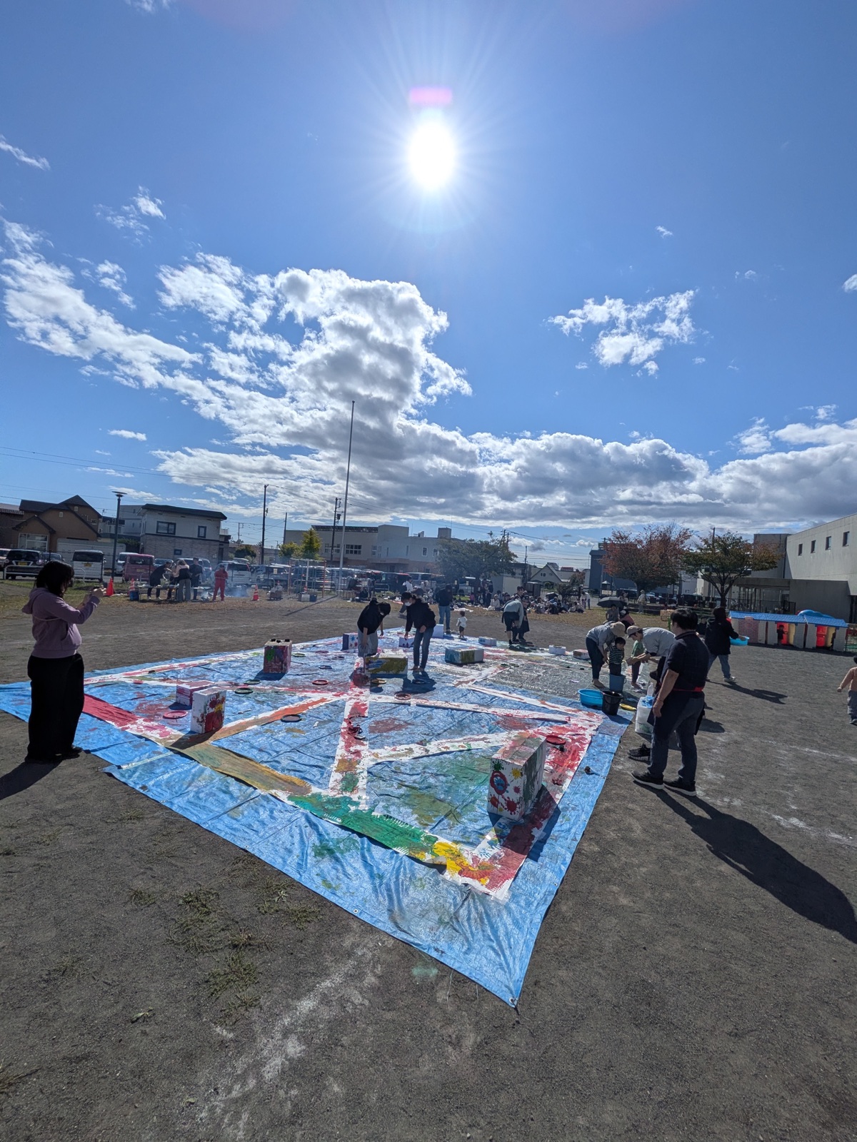 青空の下、広げたシートで絵の具遊びをする会場の様子